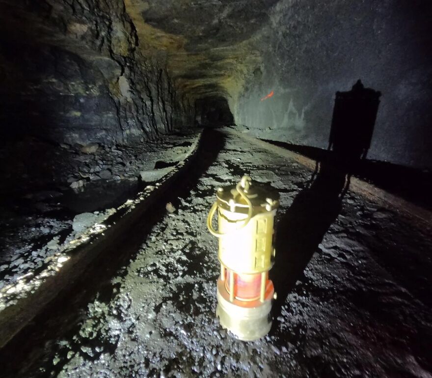 A miner's lamp illuminates a dark, narrow mine tunnel, highlighting the challenging and stressful jobs in mining.
