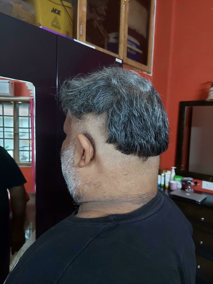 A man with a terribly uneven haircut and beard in a salon, a true beauty disaster.