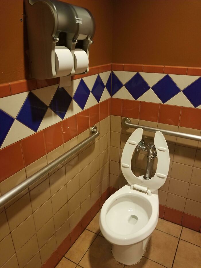Toilet in a bathroom with colorful tile walls and two toilet paper dispensers above