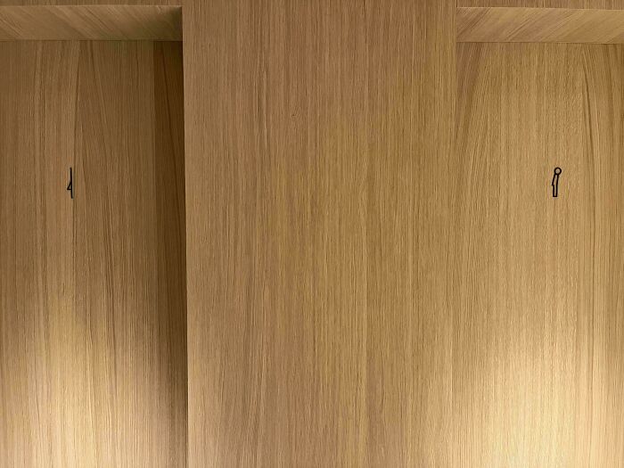 Wooden bathroom stall doors numbered 4 and 1 with unclear gender signage