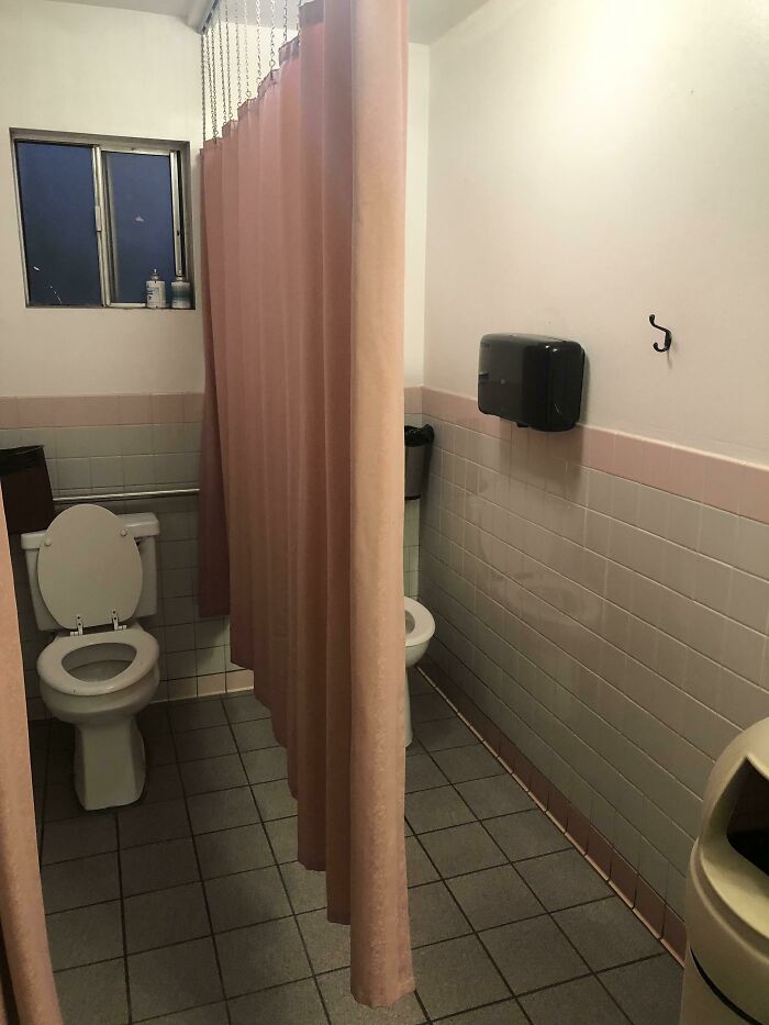 Bathroom with two toilets separated only by a shower curtain dividing the space