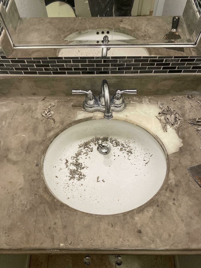 Dirty bathroom sink with debris and worn countertop in poor bathroom design