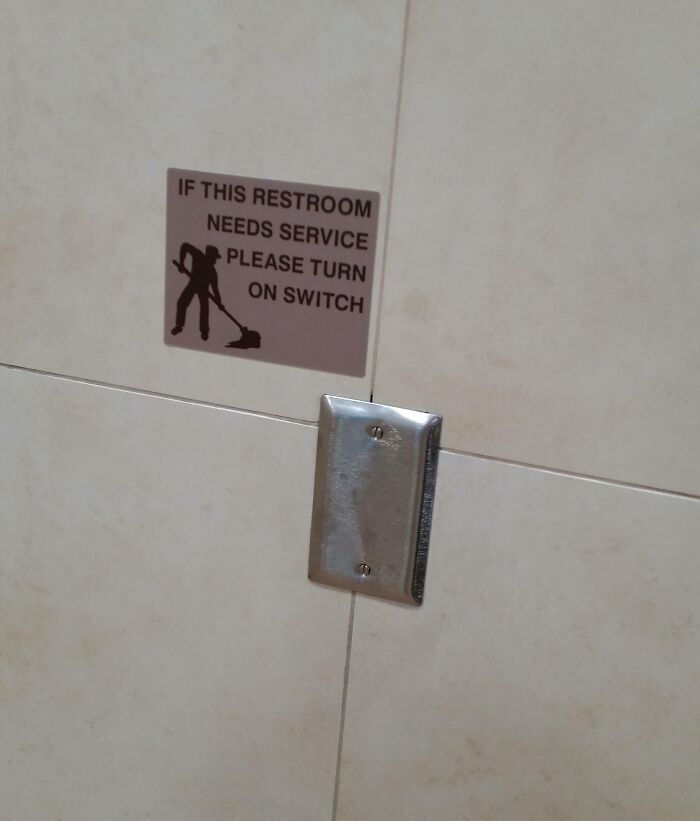Restroom service switch on tiled bathroom wall with cleaning instructions sign