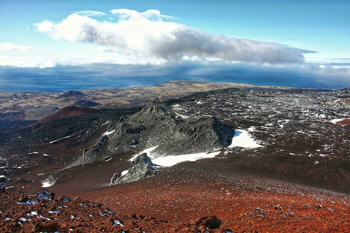 Stunning volcanic landscape with rocky terrain and ocean views under cloudy sky
