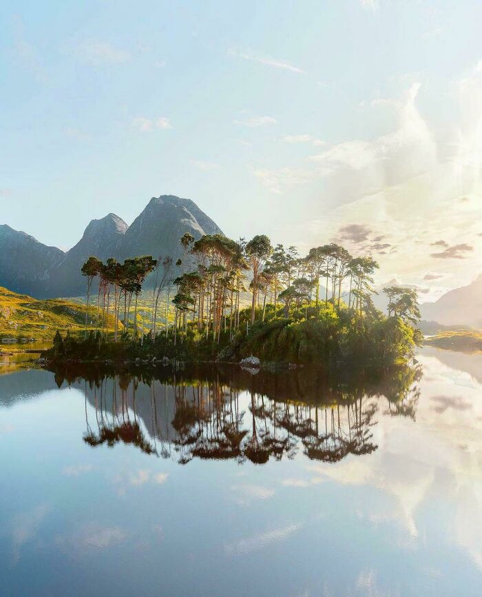 Sunlight illuminating trees on small island with stunning lake reflection views