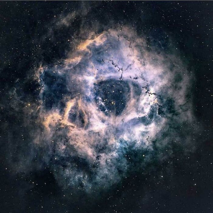 A cosmic nebula, shimmering with blue, white, and gold gases, against a dark starry background. High strangeness in space.