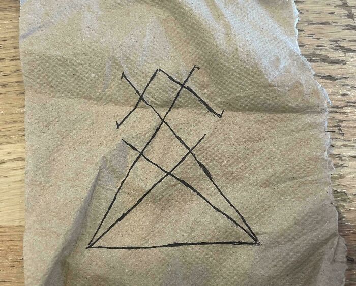 A mysterious symbol drawn on a crumpled piece of brown paper, evoking high strangeness and a rabbit hole.