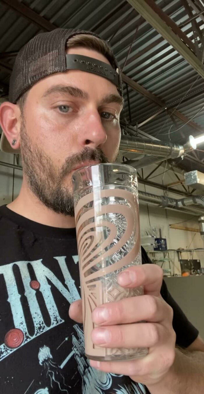 Man drinking from a patterned glass in industrial setting