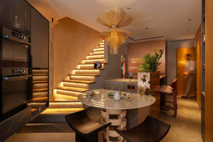 Modern interior design with illuminated staircase and dining area showing cleaning oversight