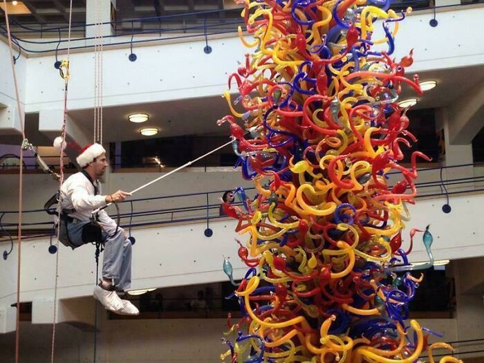 Man cleaning or working on large colorful glass chandelier