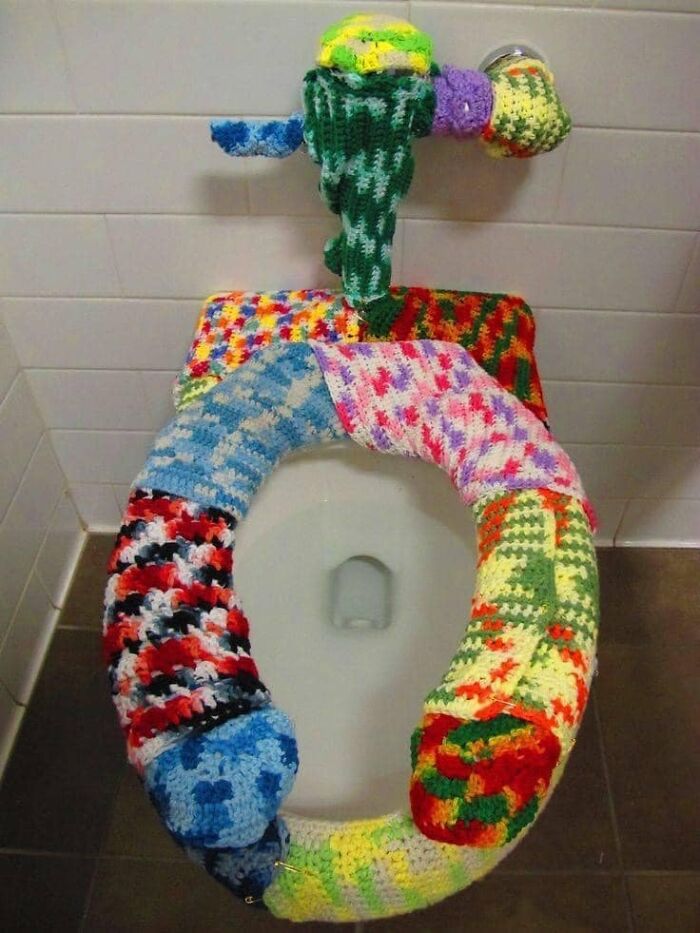 Toilet with colorful knitted covers on seat and water handle