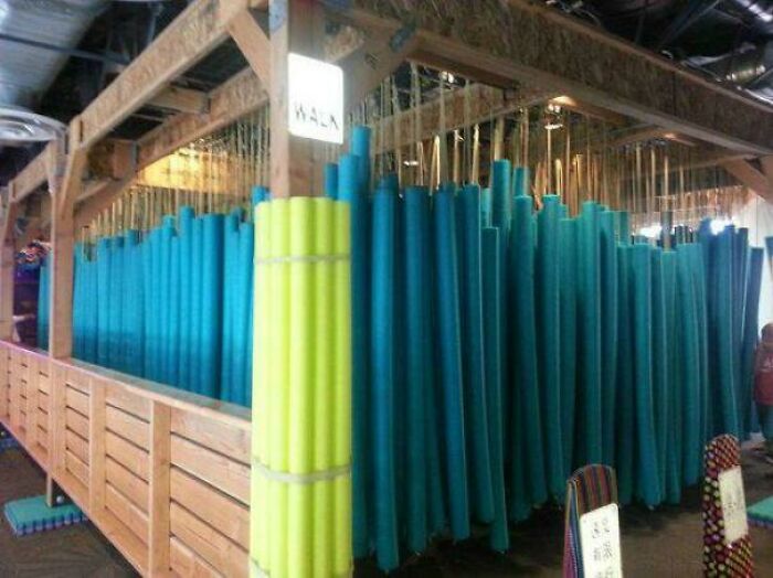 Pool noodles hanging vertically in wooden frame display