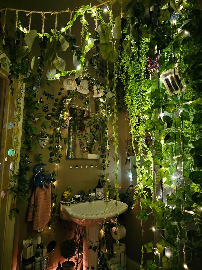 Bathroom decorated with excessive hanging plants and string lights