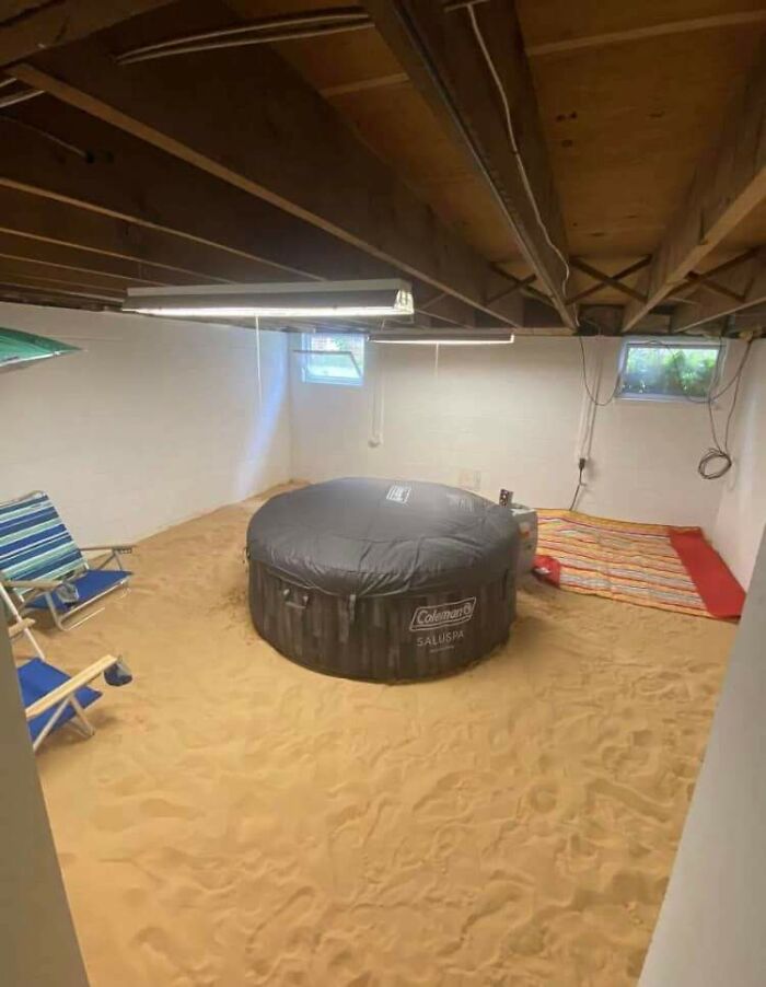 Basement room with sand-covered floor and inflatable spa