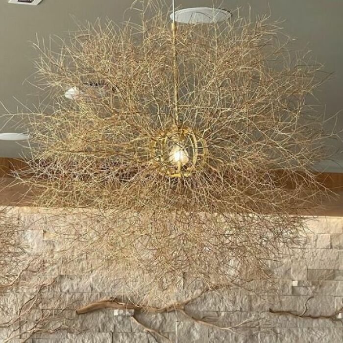 Tangled branch chandelier hanging in living space with stone wall