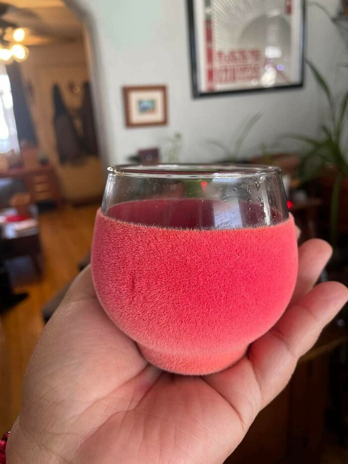 Glass cup covered in pink fuzzy texture held in hand