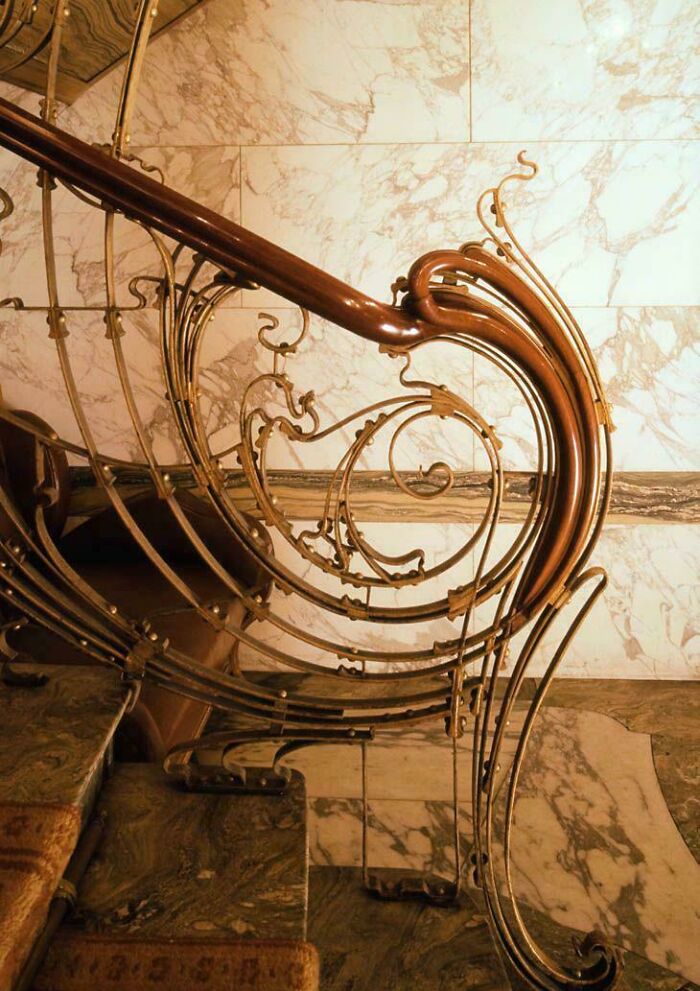 Art Nouveau style curved stair railing with marble background