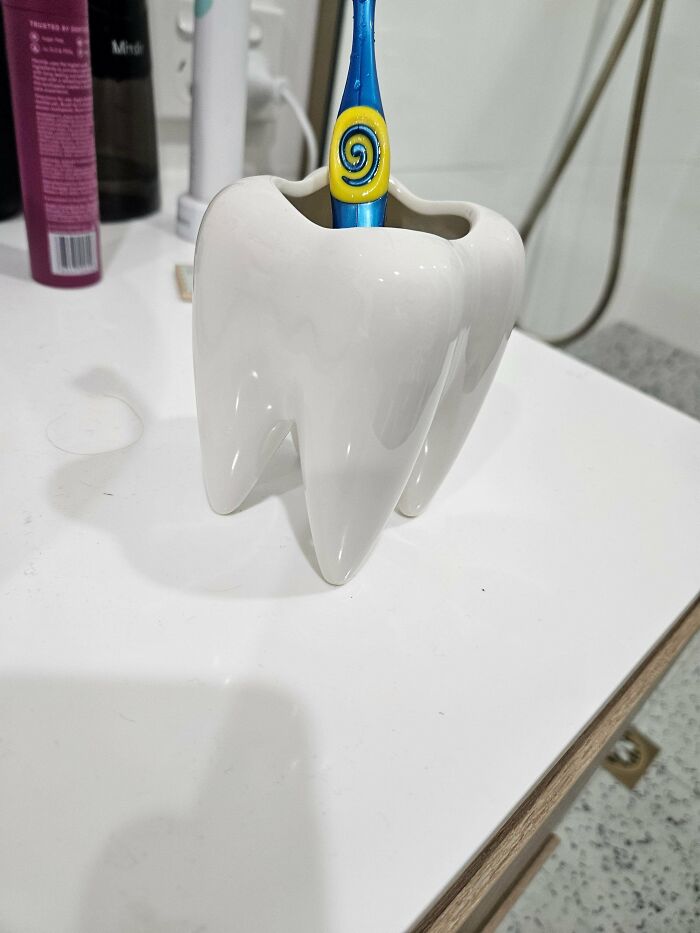 Tooth-shaped toothbrush holder design sitting on bathroom counter