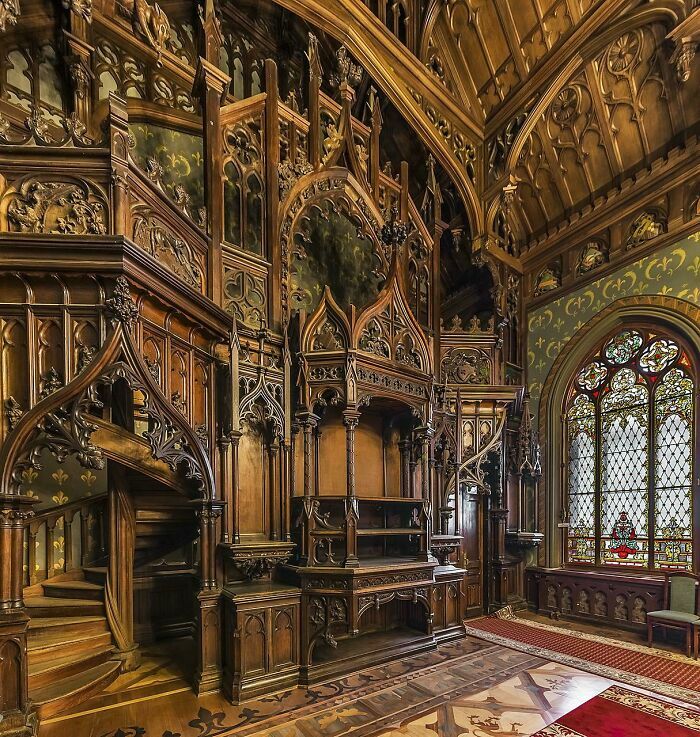 Intricately carved wooden room with gothic style architecture and stained glass window