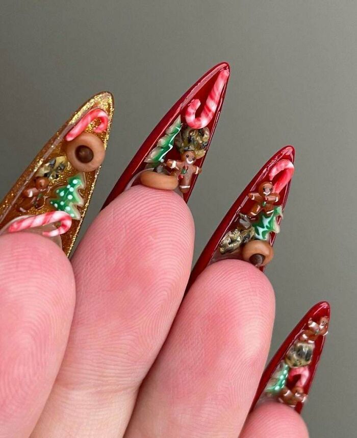 Close-up of long red nails adorned with detailed Christmas-themed miniature decorations