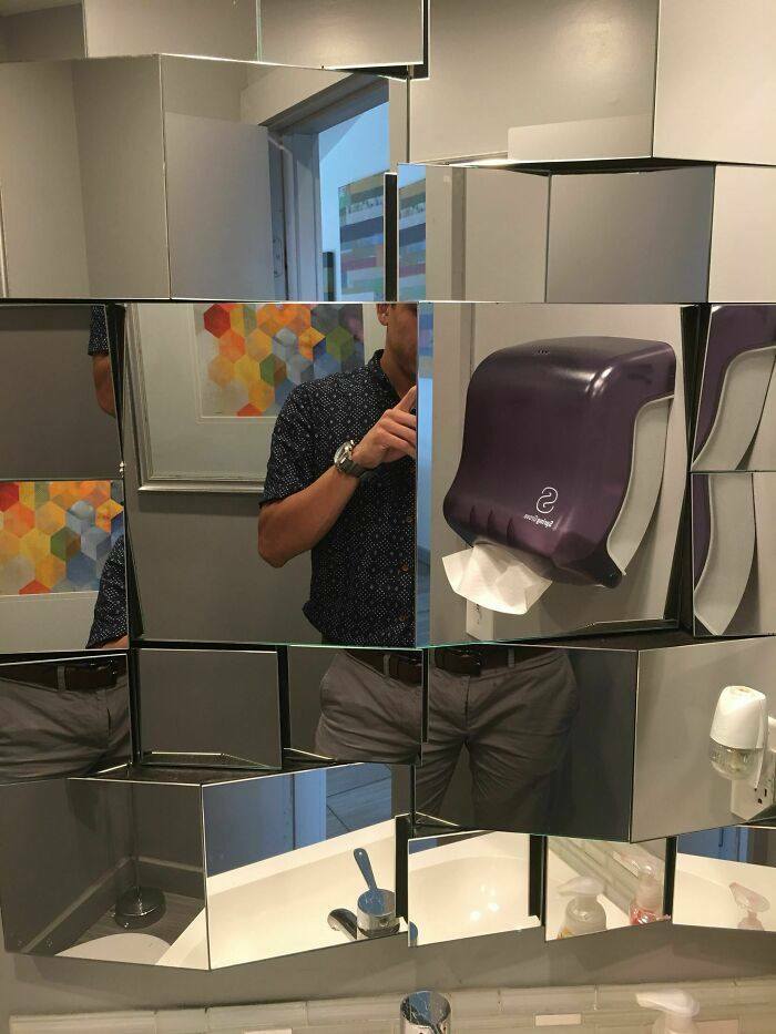 Irregular tiled mirror wall with a paper towel dispenser, dusty
