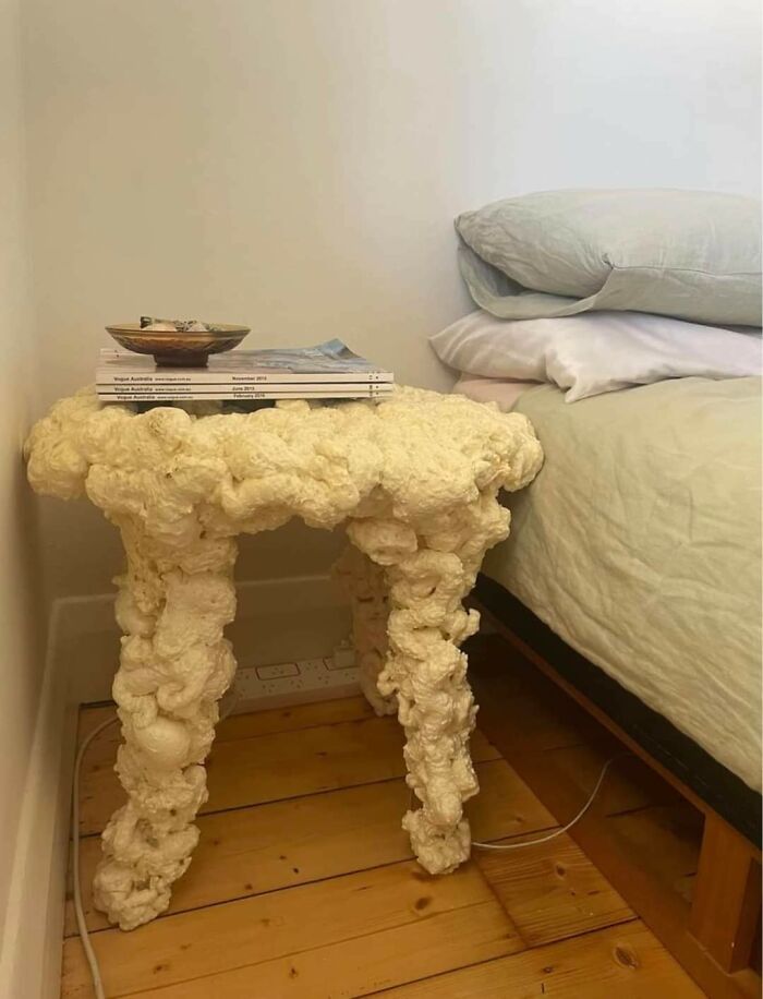 Side table made of rough textured spray foam next to bed displays unconventional design
