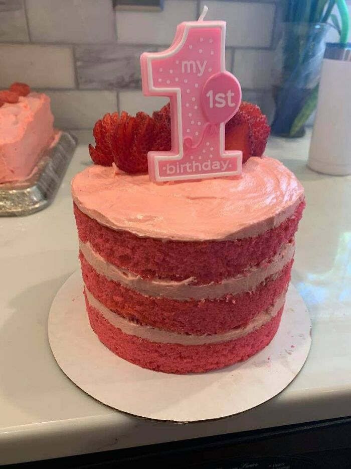 Pink layered cake with strawberries and first birthday candle