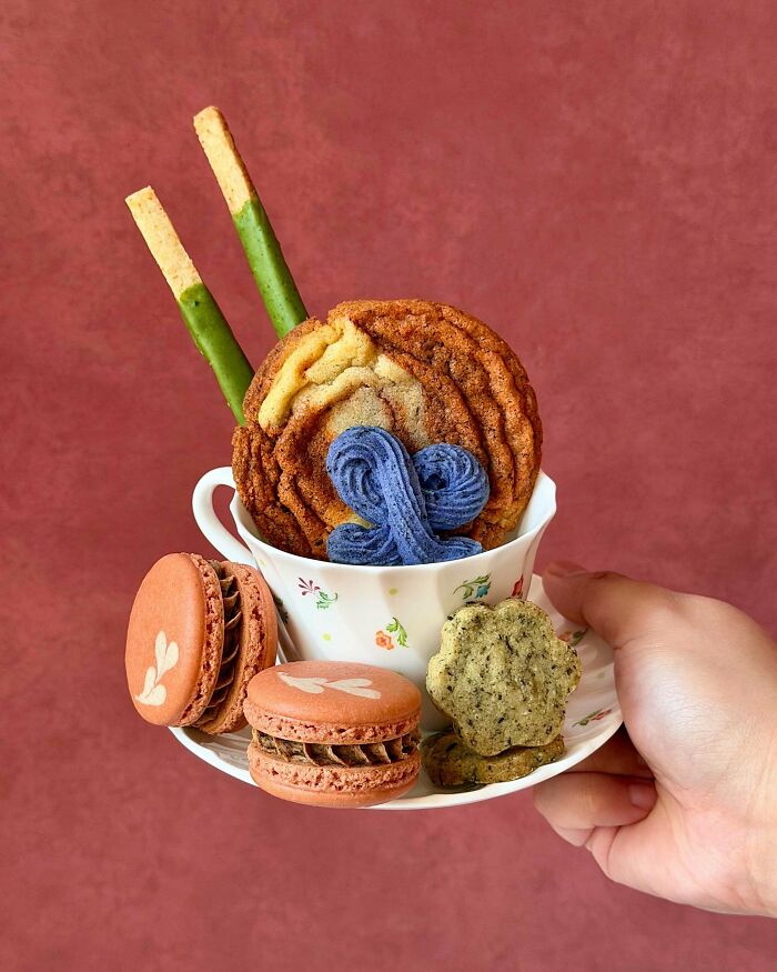 Assorted cookies and macarons arranged in teacup dessert