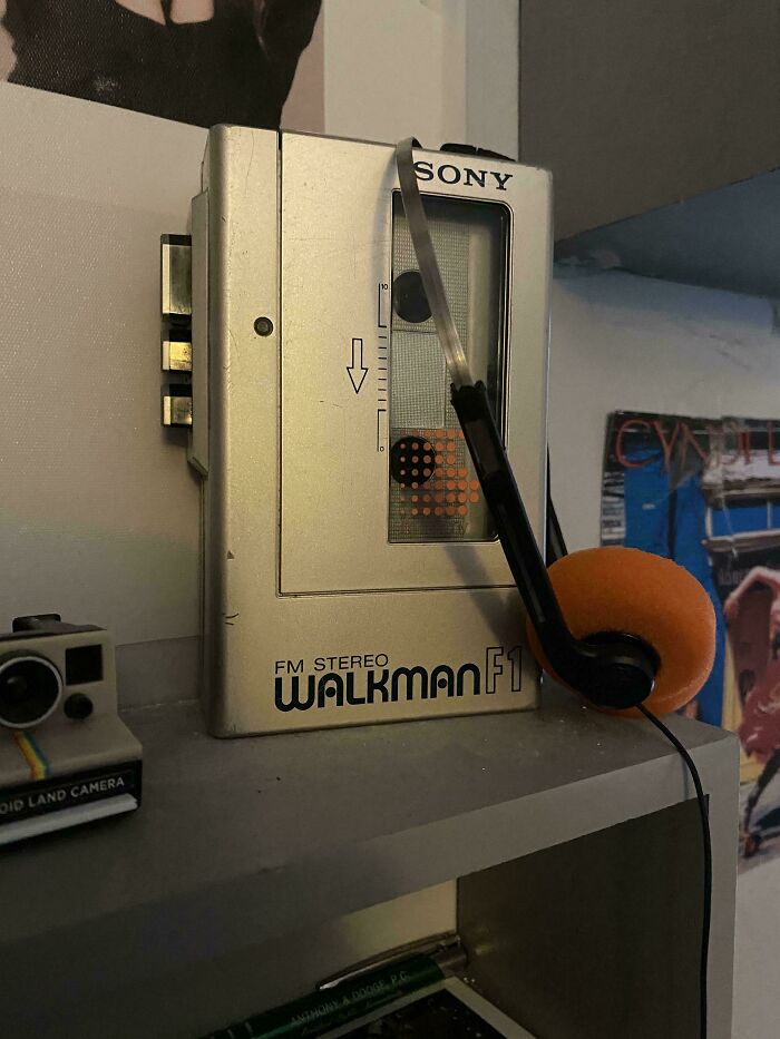 A vintage silver Sony Walkman F1 with orange foam headphones, reflecting a retro pic of older times.