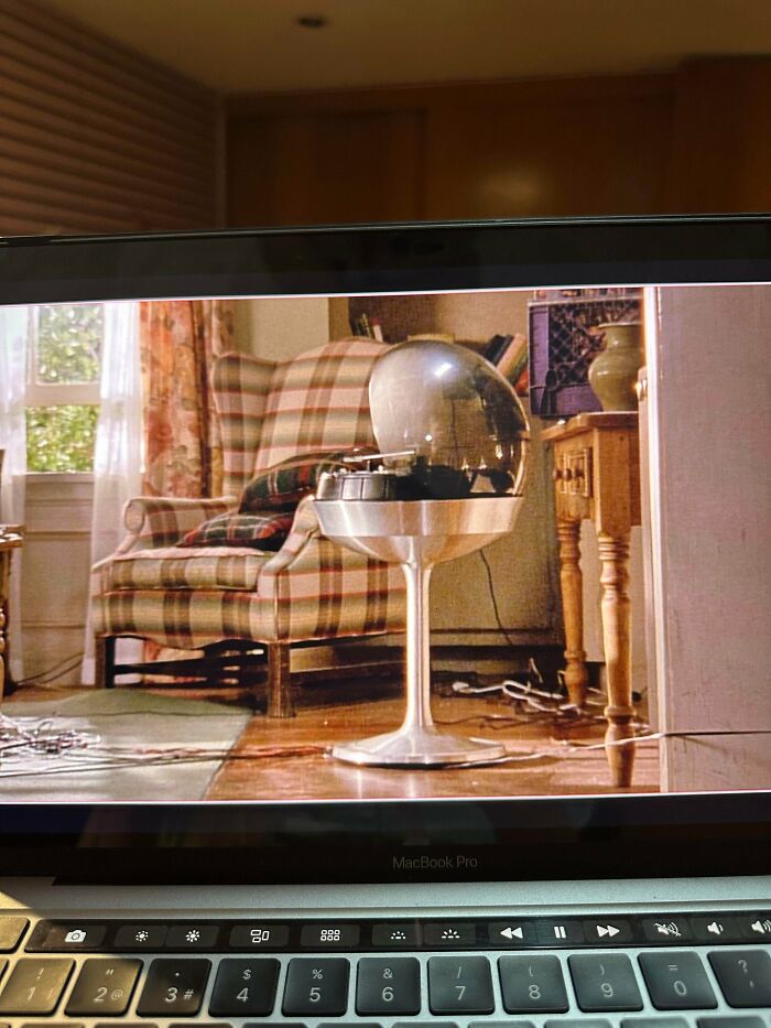 A laptop screen showing a retro pic of a 1960s living room with a chrome record player and plaid armchair, older times.