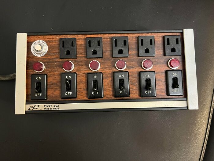 A retro six-outlet power strip with toggle switches and indicator lights. A perfect time machine into older times.