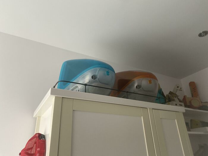 Two vintage iMac G3 computers, blue and orange, sitting atop a cabinet, a true retro pic time machine.