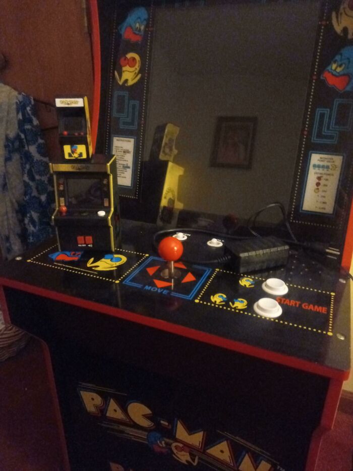 A retro Pac-Man arcade cabinet with a red joystick and buttons, and two miniature arcade machines, evoking older times.