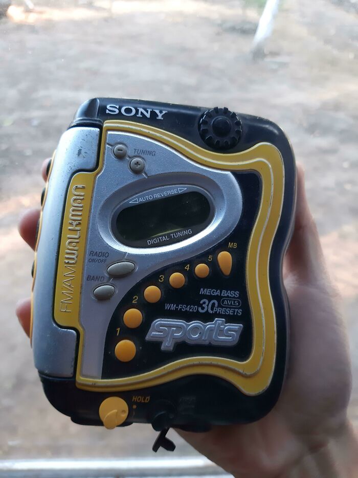A person holding a black and yellow Sony Sports Walkman. This retro pic is a time machine to older times.