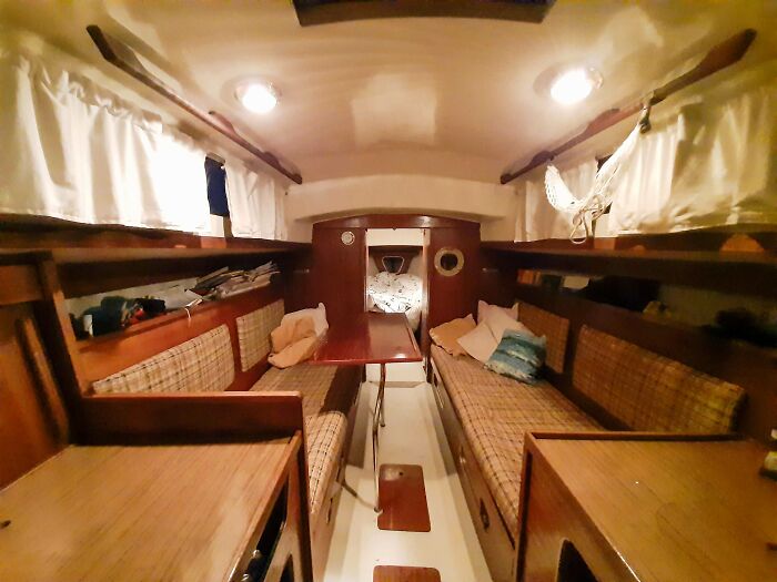 A cozy retro boat cabin with wooden interior, plaid cushions, and bright lights, showing a glimpse into older times.