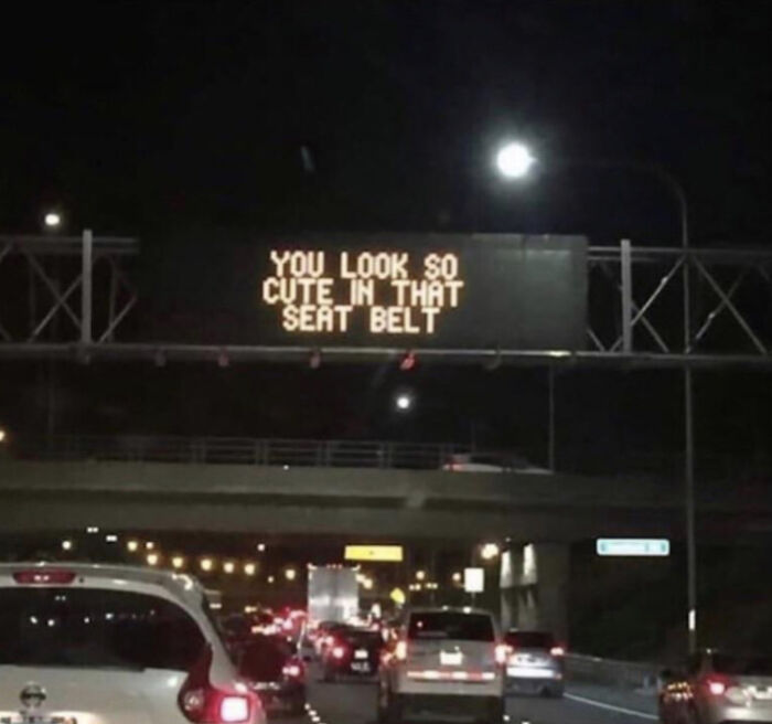 Night view of a highway sign displaying "YOU LOOK SO CUTE IN THAT SEAT BELT," a blessed image spreading positivity.