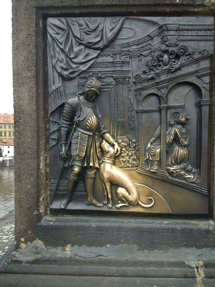 A bronze relief of a knight patting a dog, with other figures and architecture. Blessed images to make your day better.