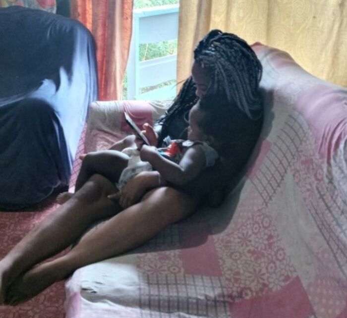 Woman and child sitting on couch indoors using phone