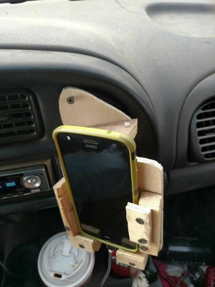 Um suporte de telefone de madeira caseiro montado no painel de um carro. Uma história em escala inteligente poderia estar relacionada ao uso do telefone.