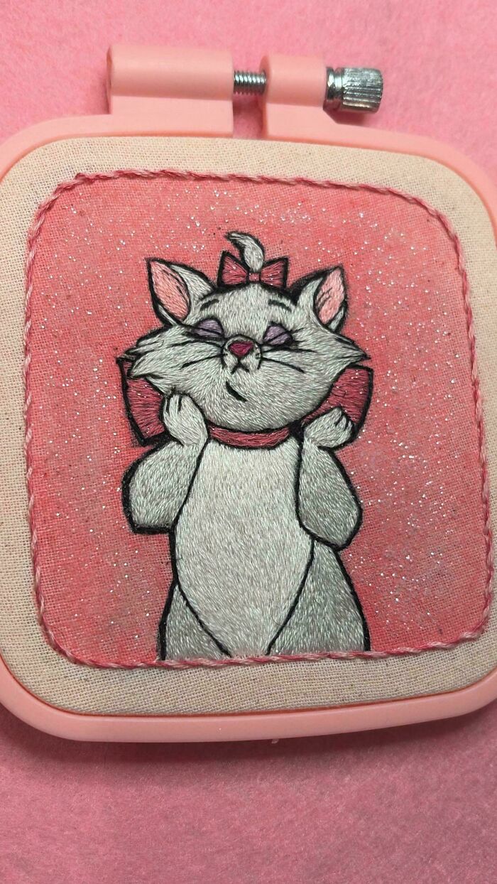 Cute embroidered cat character on a pink glittery background from creative embroidery projects.