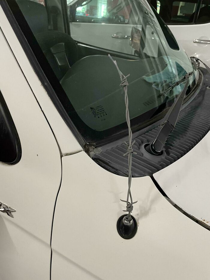 A piece of barbed wire used as a car antenna, demonstrating clever solutions with random junk.