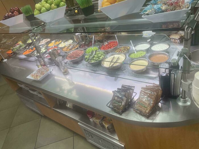 Salad bar with various fresh ingredients behind glass display