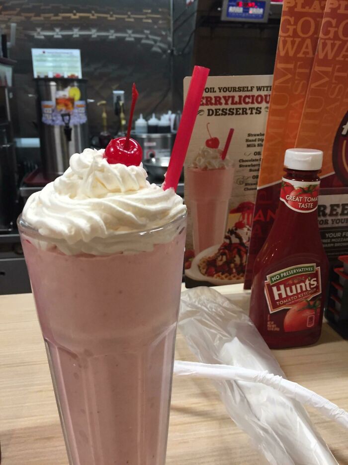 Strawberry milkshake with whipped cream and cherry at dessert counter