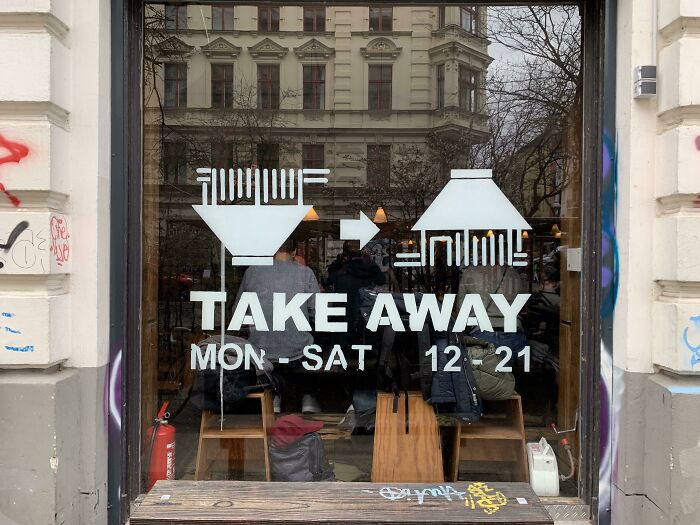 Restaurant window with take away hours and noodle bowl graphics