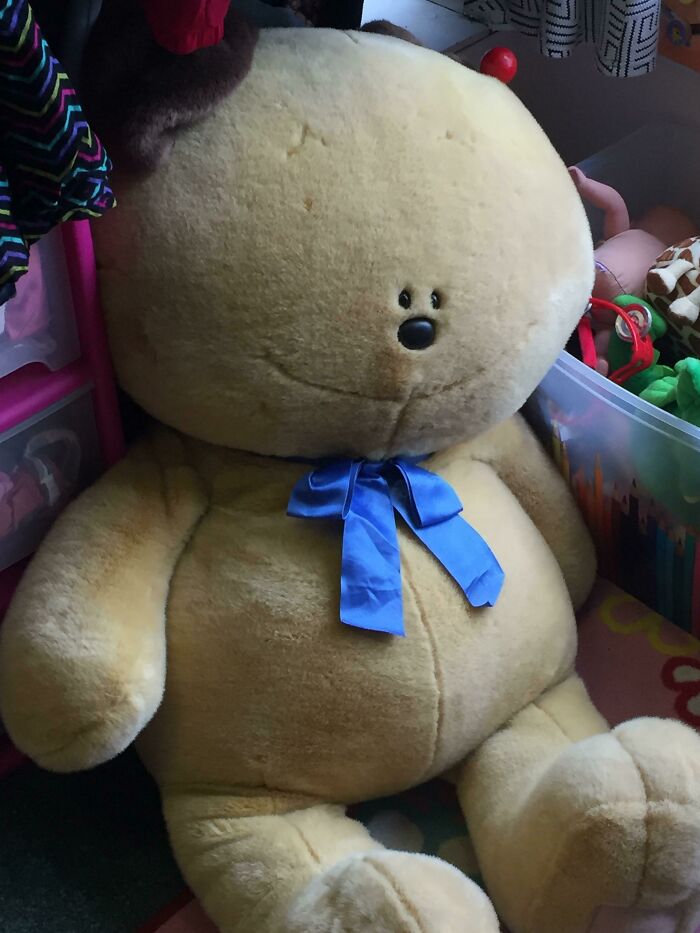 Large absurd secondhand plush bear with a blue ribbon bow