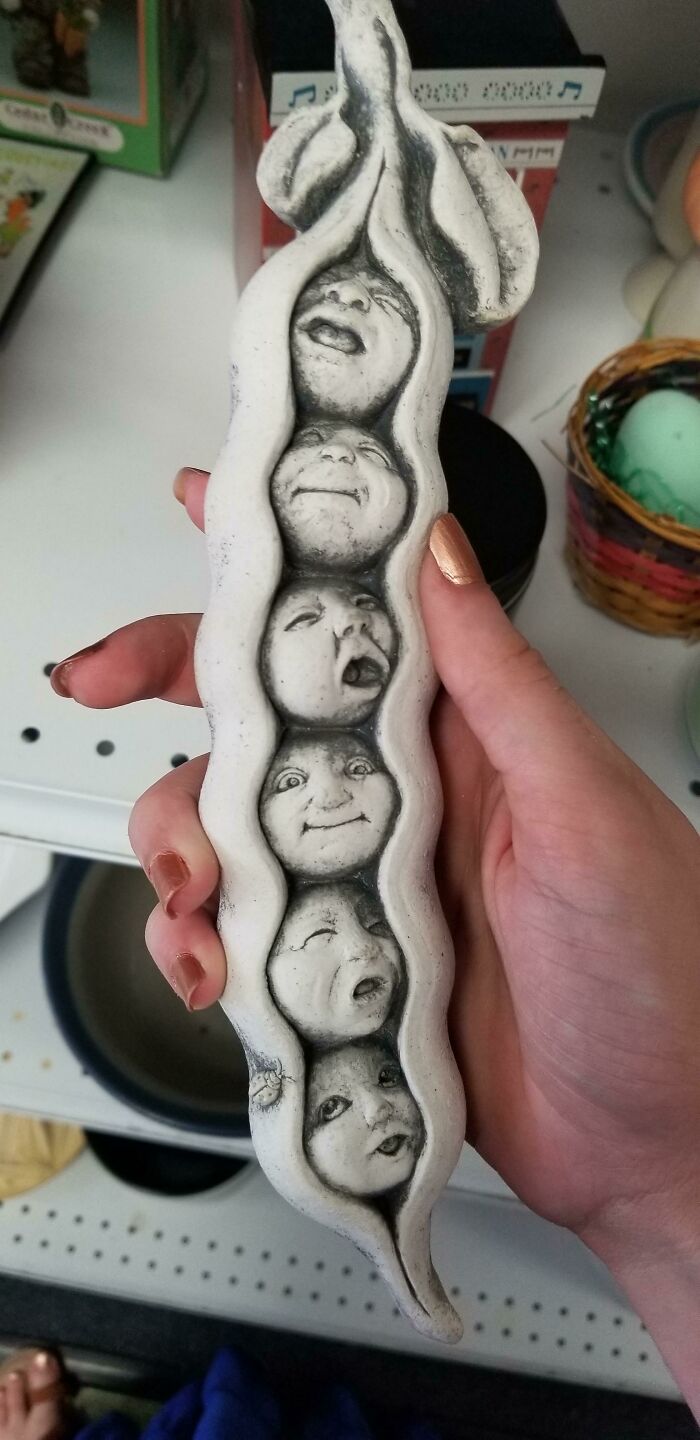 Absurd secondhand ceramic sculpture of a pea pod with human faces held in hand
