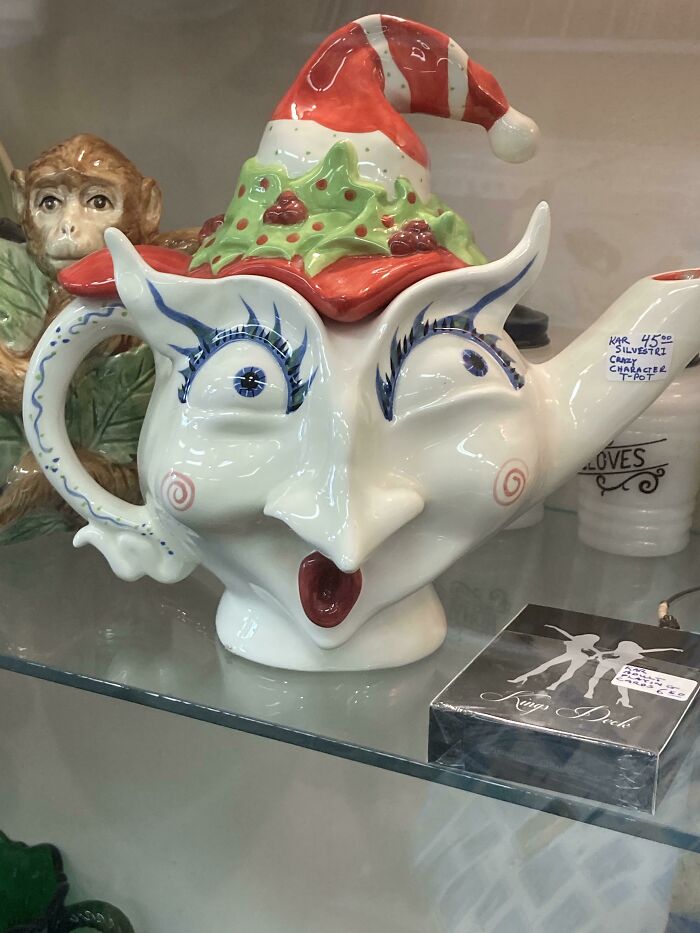 Absurd secondhand Christmas teapot with expressive face and Santa hat on display