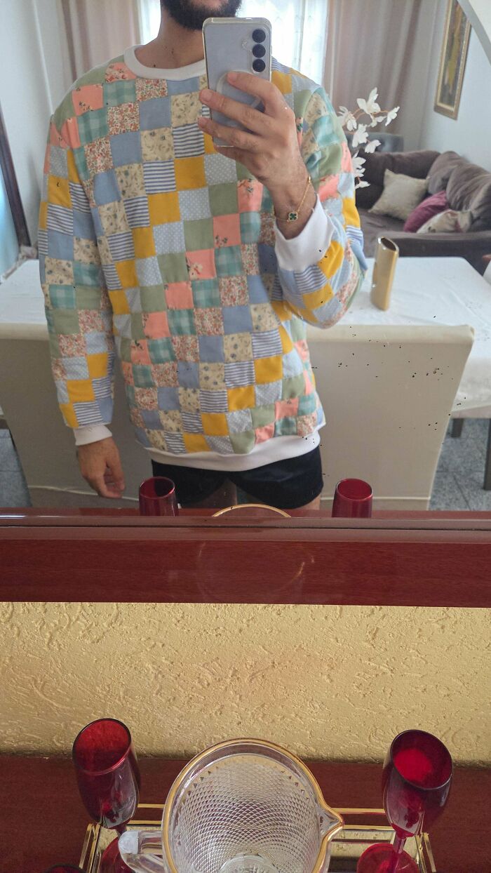A person wearing a colorful, handmade patchwork quilt sweater. Handmade projects that took talent, patience, and a little magic.