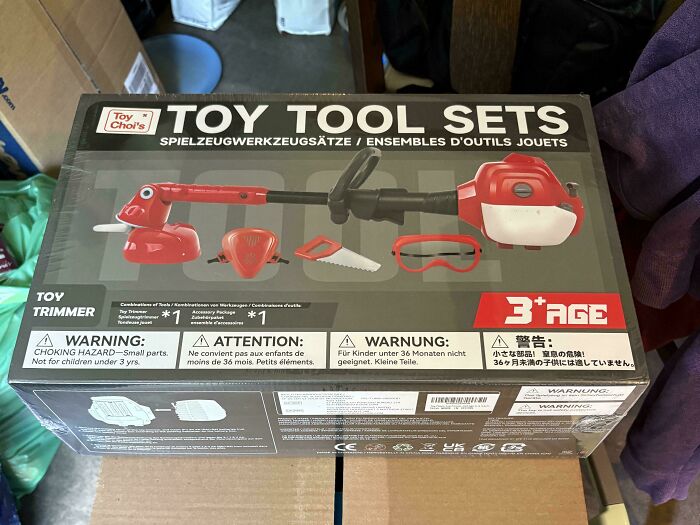 A boxed toy tool set with a toy trimmer, saw, and safety goggles, highlighting the price difference and consumerism.