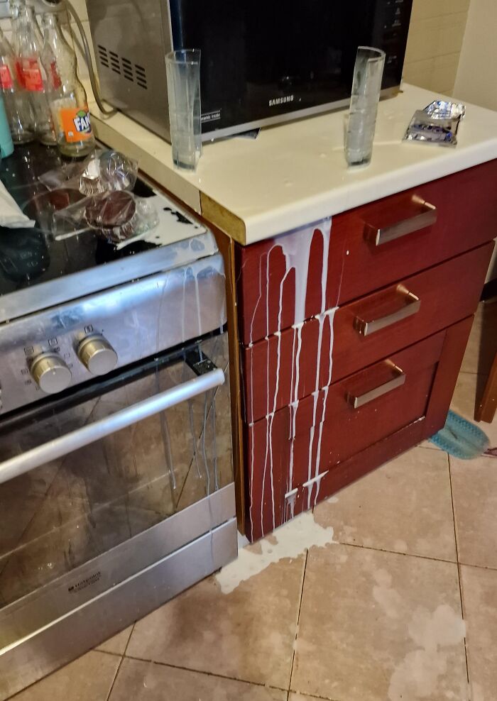 Kitchen fail with spilled milk dripping down kitchen cabinets and floor